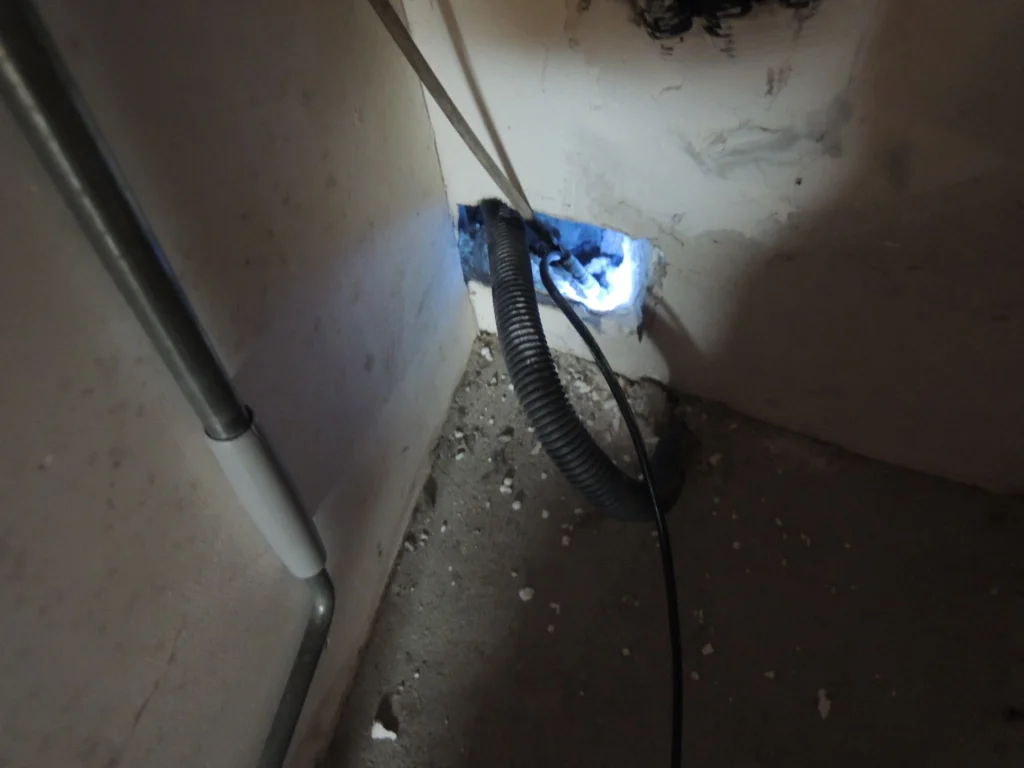 Passage de câble de fibre optique à travers un mur avec une gaine annelée noire